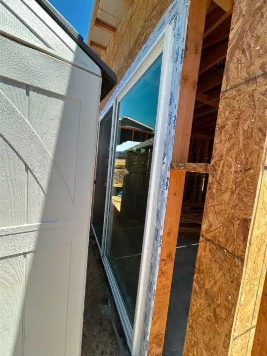 Window flange sealed with flashing tape over OSB exterior sheathing on a cabana wall.