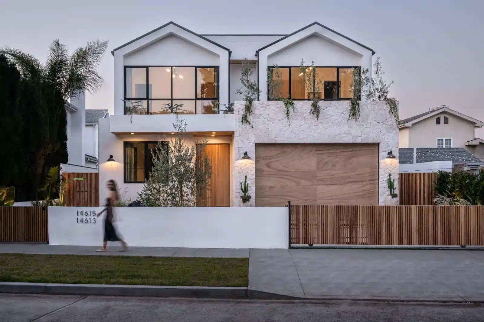 Finished home exterior with white walls, black-framed windows, textured cladding, and a wood-grain garage door