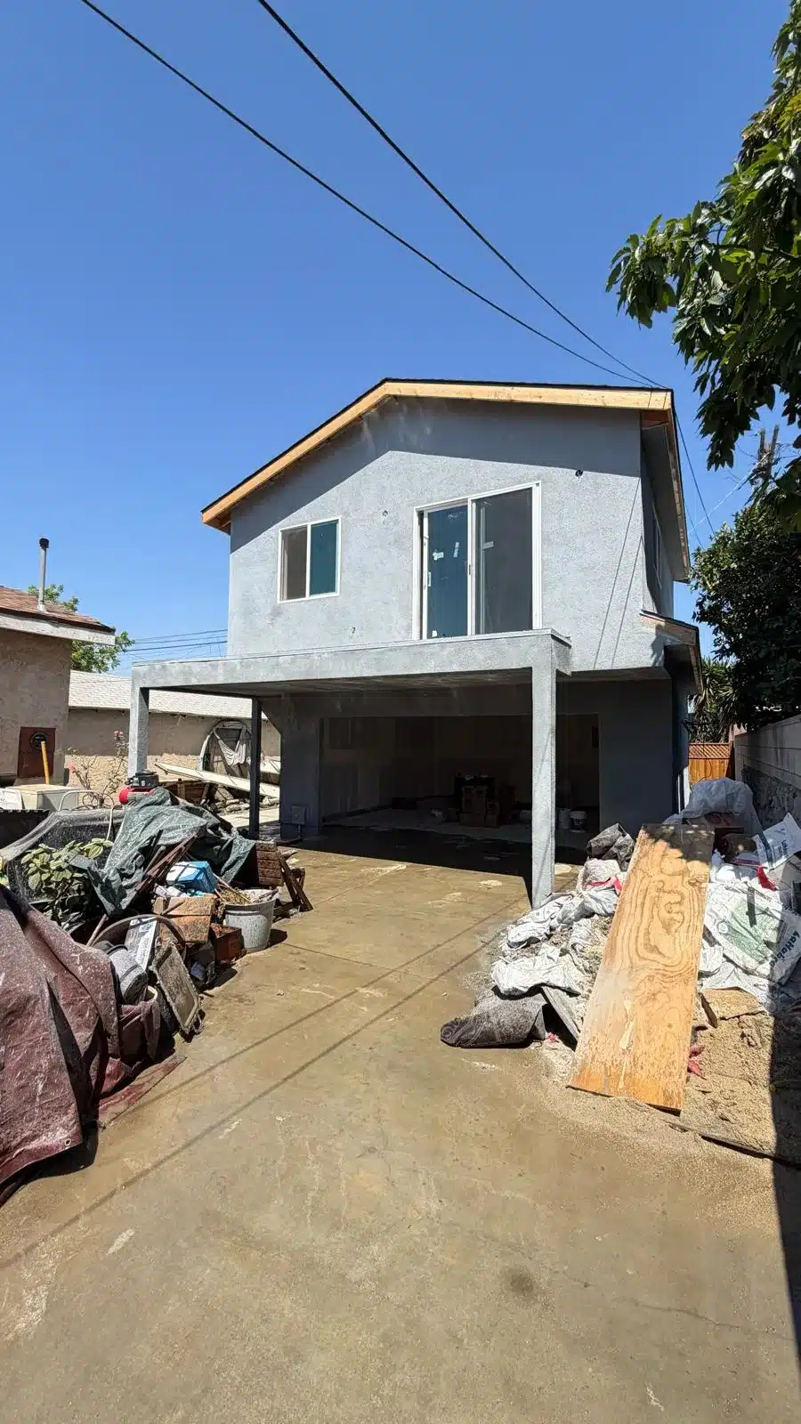 Two-story stucco structure under construction by IBA Builders with materials staged along the driveway