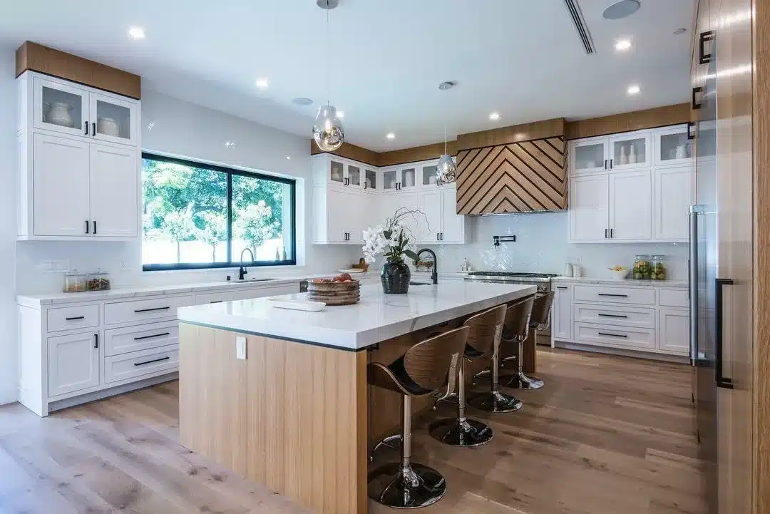 Finished kitchen with white cabinets, a wood-grain island, pendant lights, and a wide window above the sink